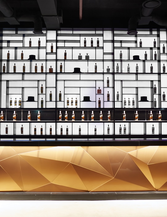 Gangnam's seven-story Johnnie Walker House has a striking copper exterior that reflects light during the day and transforms into a whisky bottle at night. Inside, visitors can explore a retail space, rooftop bar, club, VIP whiskey lounge, cocktail school, and a whiskey-themed restaurant with interactive technology and whiskey-inspired design. Design by Studio Königshausen.